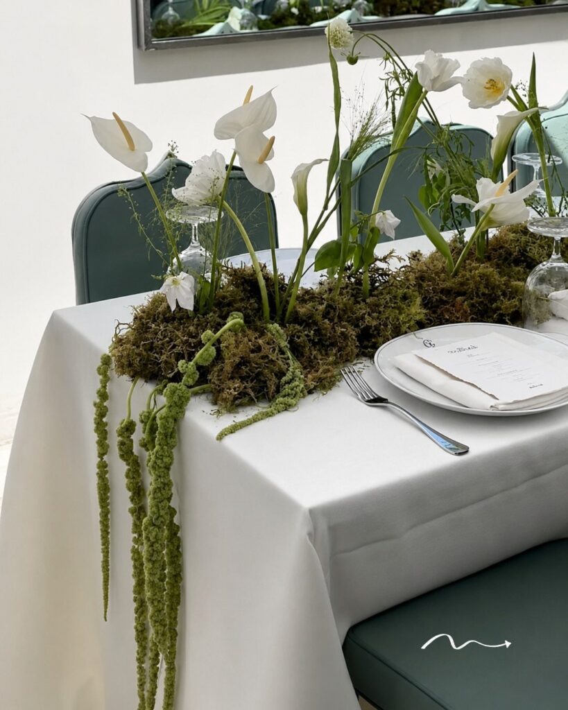 White calla lilies and moss centerpiece on a white wedding table setting