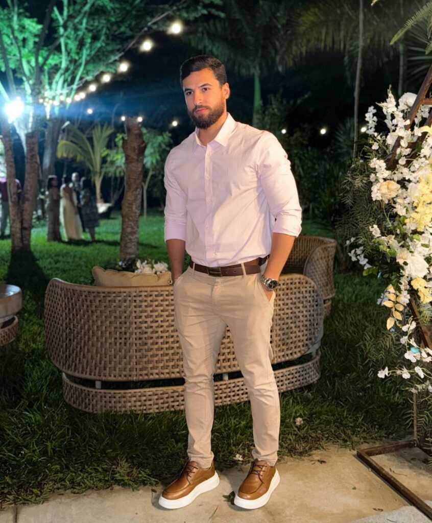 Man wearing a white button-up shirt and khaki pants at an outdoor event.