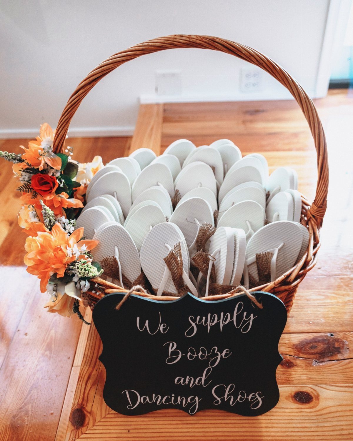 Wicker basket filled with white flip-flops and a sign for dancing shoes.