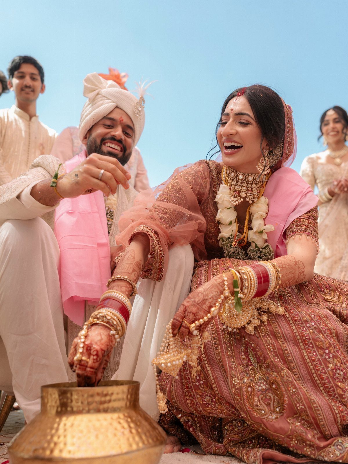 Indian bride in red embroidered lehenga and jewelry smiling during wedding ceremony