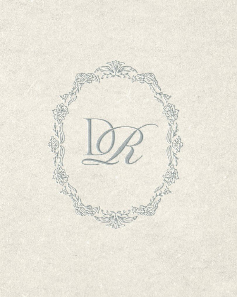 Intertwined letters D and R inside a decorative floral oval frame on paper.