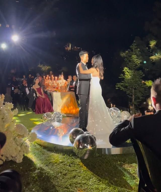 Bride and groom embracing on a reflective dance floor during a nighttime wedding reception.