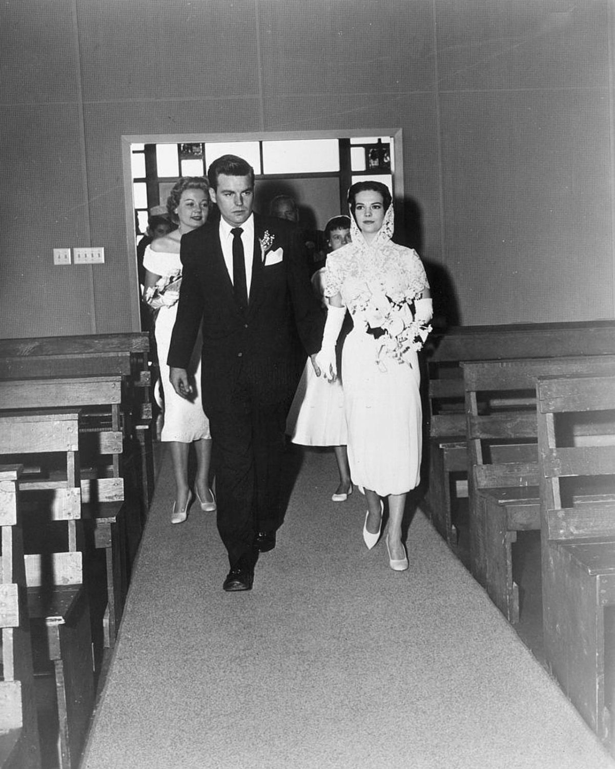 Bride and groom walking down a church aisle in vintage wedding attire.