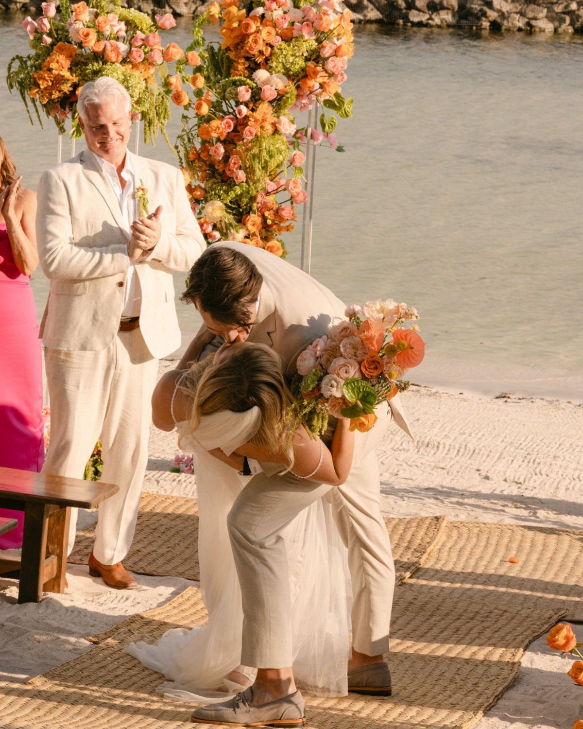 Bride and groom kissing on a beach during a tropical wedding ceremony.