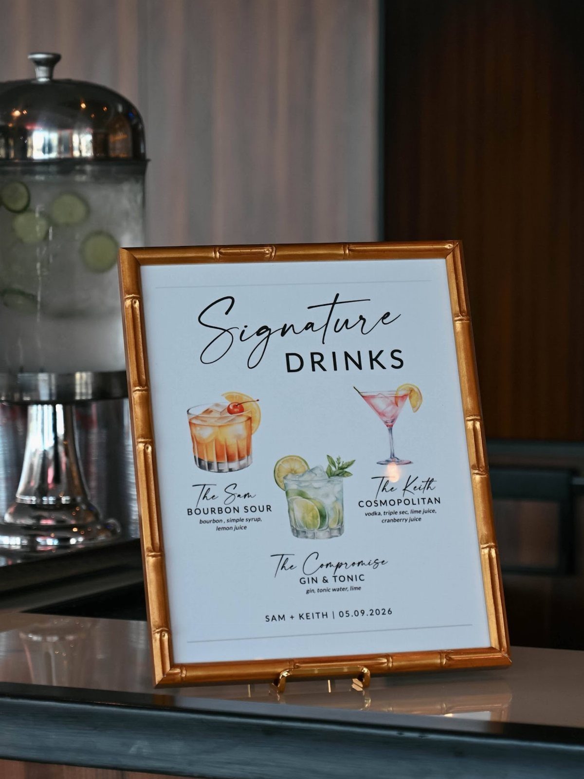 Gold framed signature drinks menu with cocktail illustrations on a wedding bar counter