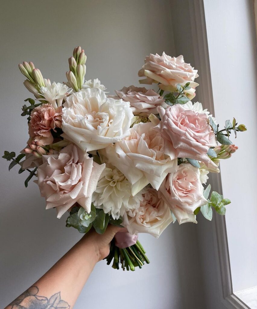 Bridal bouquet with blush and cream roses and green eucalyptus leaves.