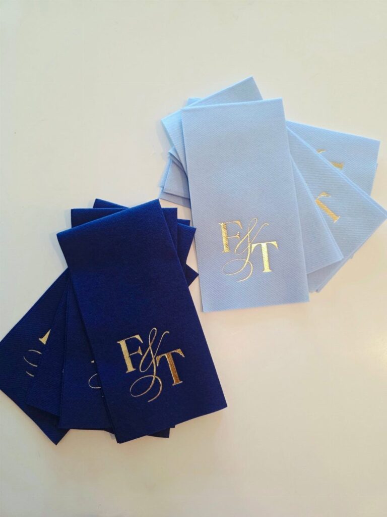 Navy and light blue fabric napkins with gold foil monogrammed initials F&T.