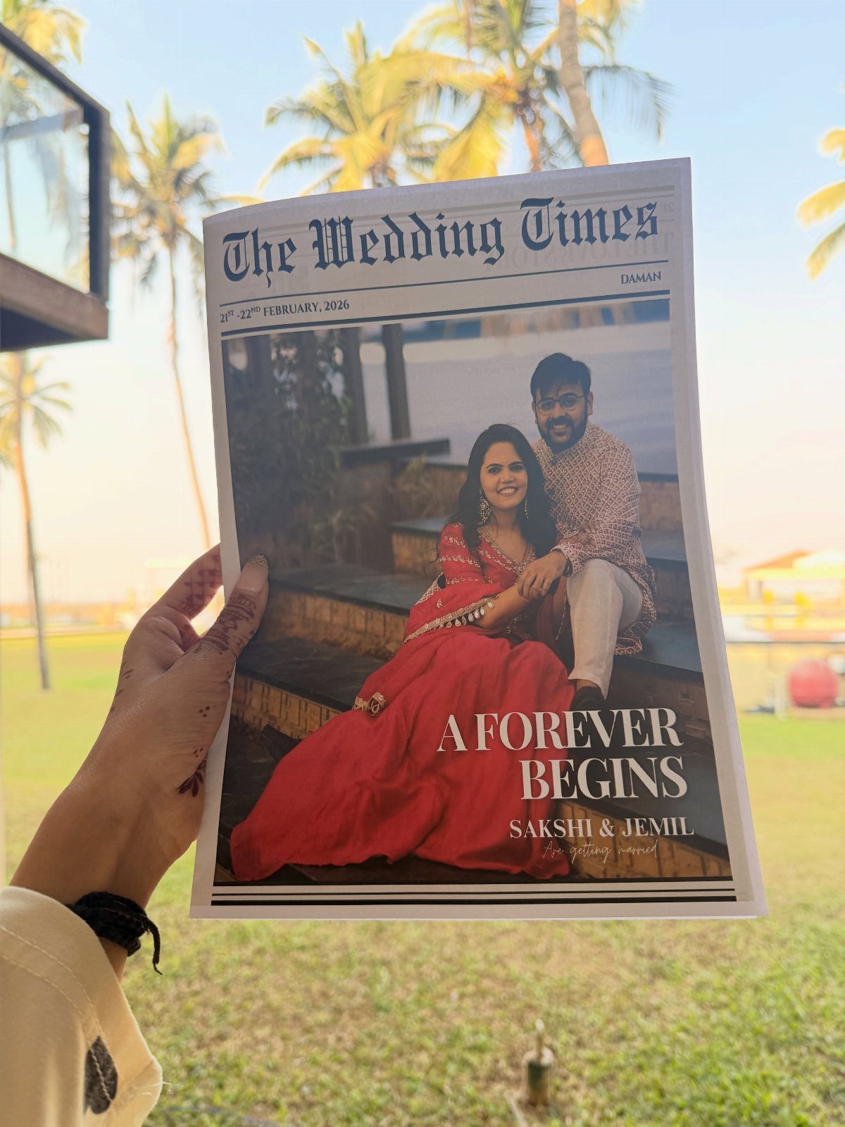 Wedding newspaper held by a hand featuring a couple in traditional Indian clothing.