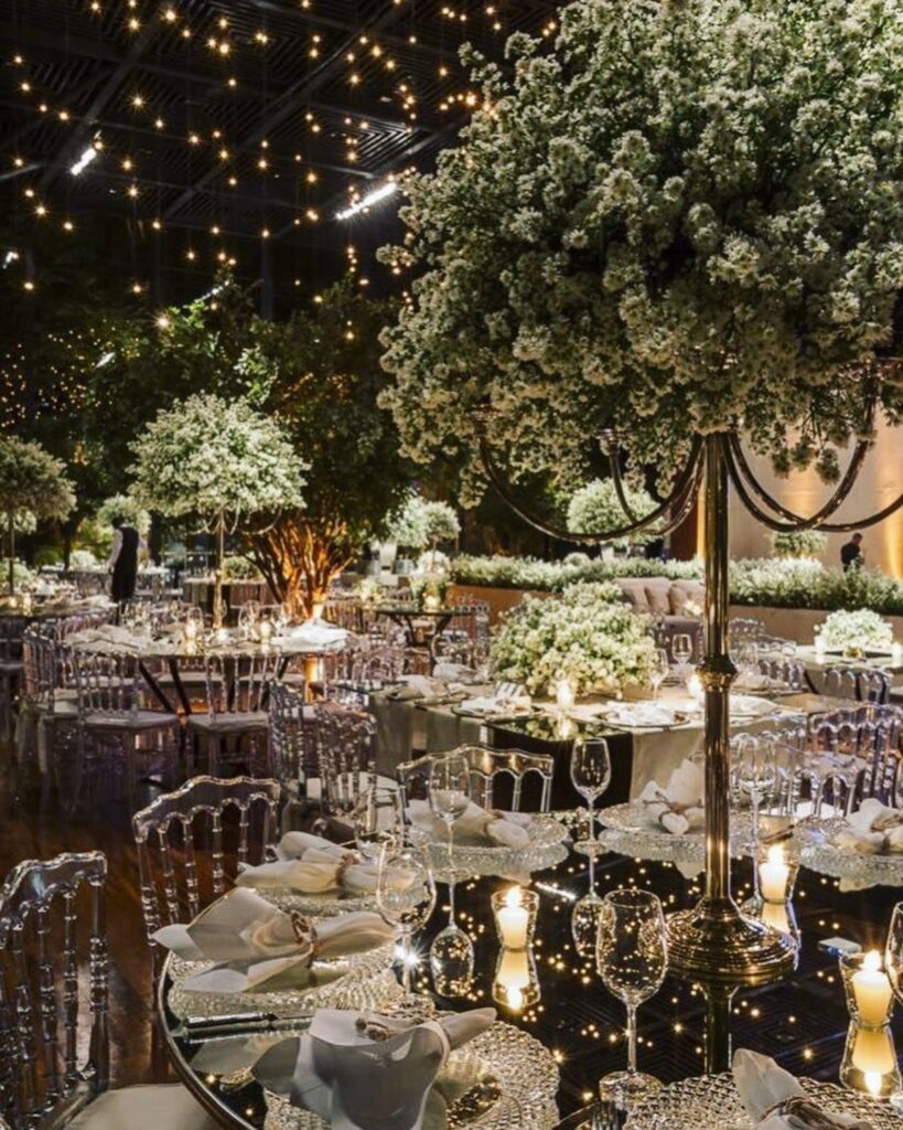 Elegant wedding reception with white floral centerpieces and fairy lights on the ceiling