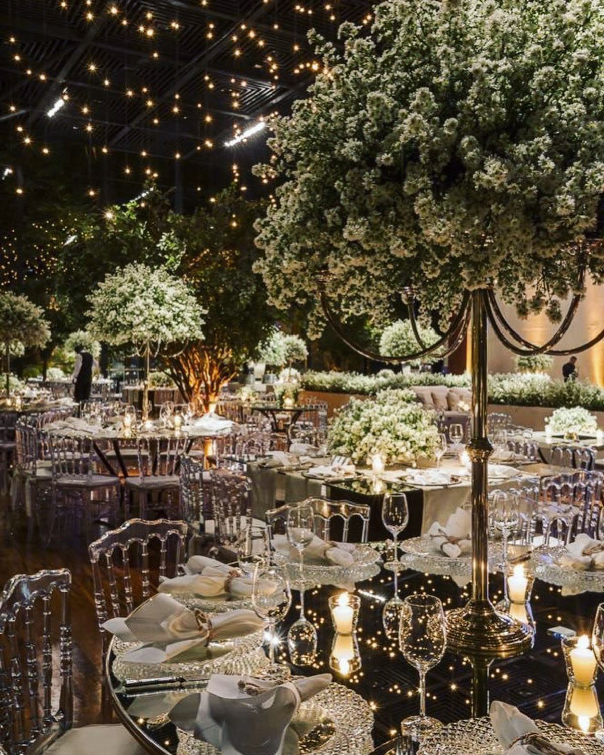 Elegant wedding reception with white floral centerpieces and fairy lights on the ceiling